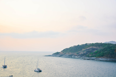 Grass blowing on a PromThep cape in Phuket Thailand with the scenery of island, blue sea and partly cloud.の写真素材