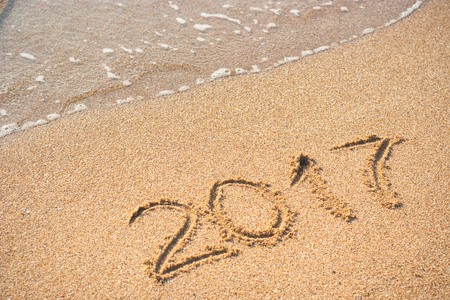 2017 written on empty wet yellow beach sand washed by sea wave