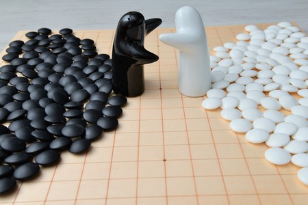 Go game pieces and two black and white figures on go boardの写真素材