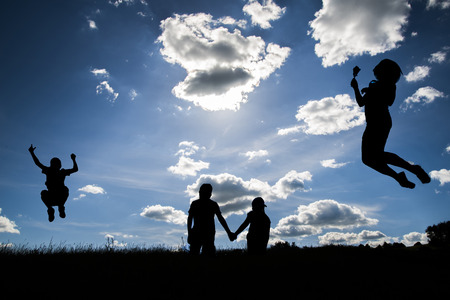 The silhouettes of  a women flying, a boy jumping and two young people holding hands  on the top one...