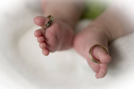 Beautiful conceptual image of  feet weeding rings put on baby feet fingersの写真素材