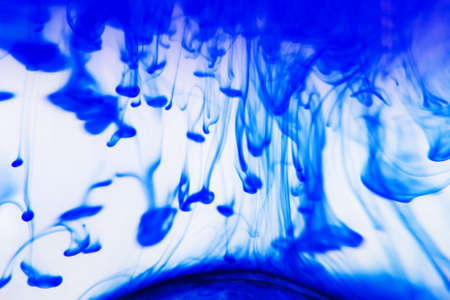 The formation of raindrops explained to children through an experiment with a clear glass bowl, cold water, shaving foam and inkの写真素材