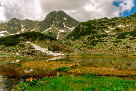 Glacial lake in the mountains landscape in summer. Lovely landscape photography of a mountain lake with mountain peaks in the background. Weather is sunny with a couple pf clouds.の写真素材