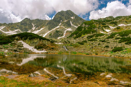 Glacial lake in the mountains landscape in summer. Lovely landscape photography of a mountain lake with mountain peaks in the background. Weather is sunny with a couple pf clouds.の写真素材