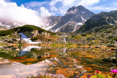 Lovely portrait photography of a mountain lake with mountain peaks in the background. Weather is sunny with a couple pf clouds. Glacial lake in the mountains landscape in summerの写真素材