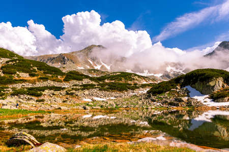 Glacial lake in the mountains landscape in summer. Lovely landscape photography of a mountain lake with mountain peaks in the background. Weather is sunny with a couple pf clouds.の写真素材