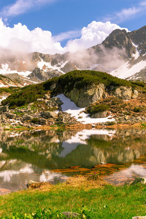 Glacial lake in the mountains landscape in summer. Lovely landscape photography of a mountain lake with mountain peaks in the background. Weather is sunny with a couple pf clouds.の写真素材