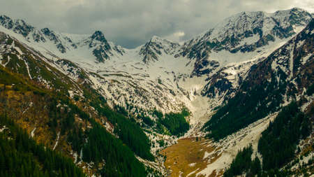 Panoramic view of the Carpathian mountains in spring time, with the peaks covered in snow. Photography was shot from a drone at a higher altitude.の写真素材