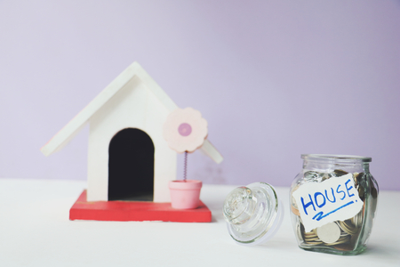 Jars of coins save money and model home on a white background.の写真素材