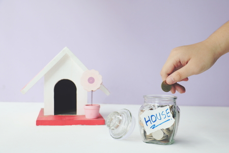 Jars of coins save money and model home on a white background.の写真素材
