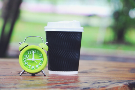 green clock and cup of coffee on wood black ground.の写真素材