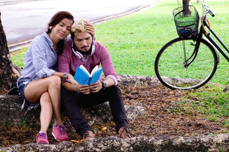 A man wear earphone for woman listen to music .They are in love in public park Thailand.の写真素材
