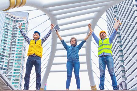 Working engineer.They are join hands  mean teamwork and spirit beside  building background.Photo...