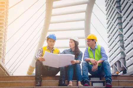 Working engineer. They are talking and plant for work with equipment beside building background....