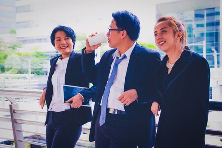 Business team.They are talking about Business.A man hold a cup of coffee and woman hold tablet.They are standing on walkway.Photo concept Business team.の写真素材
