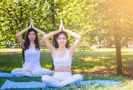 Group people have meditation for yoga.In the morning they are sitting on mat and play yoga in park.good air,hobby,Zen,Photo concept freedom and good health.の写真素材