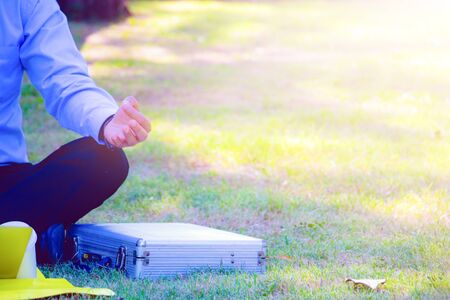 Businessman and relax time.Body part.he is sitting and meditate in public park.In front of on the floor a glass of coffee.Photo concept  business and relax time.の写真素材