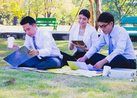 Business team work.They are talking in the park.they are talking about business and on the floor had a notebook and a glass of coffee.Photo concept business and relax time.の写真素材