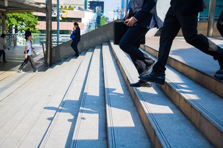 Body part business man.they are wearing black suit and carry a briefcase.They are running/walking  on staircase. Life a hurry and Business competition.Photo concept  business and succeed.の写真素材