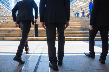 Body part business man.they are wearing black suit and carry a briefcase.They are running/walking  on staircase. Life a hurry and Business competition.Photo concept  business and succeed.の写真素材