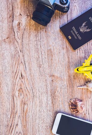 Top view accessories for travel on old wood.Cellphone,a yellow plane toy , Old camera and Thailand passport. photo concept travel and life style.の写真素材