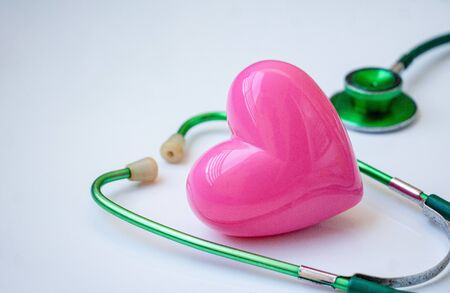 Green stethoscope and pink Heart.They are check heart wave on white background. Photo concept healthcare good feel.の写真素材