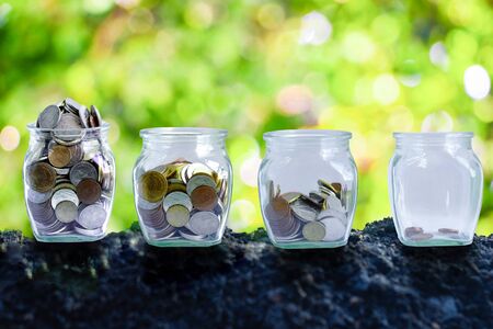 The coins in bottle on green background. The coins which are like soil in the bottle. The concept of growth for the save money.の写真素材