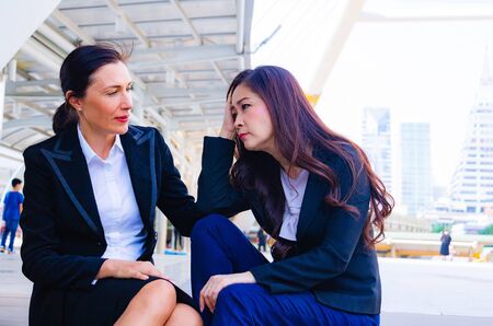 Businesswoman in town. They are sitting on walkway. She sitting with partner.She is very sad.Unhappy , depressed,Photo concept sad and Business.