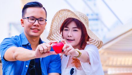 Young Asian couple are sitting on staircase. They are show  a red heart .They are smile  and happy . Photo Asian tourism and couple in Bangkok conceptの写真素材