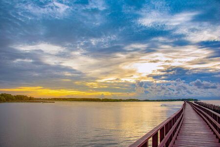 In the morning The red bridge and sun up or sun set on horizon.bridge cross sea in to the forest Thailand .Photo concept for Thailand landscape .の写真素材
