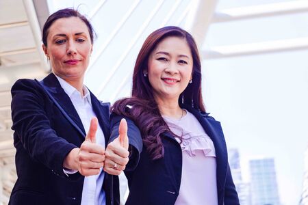 Businesswoman in town.They are standing on walkway.She standing with partner.She is point the finger in to sky.Photo concept team work and Business.の写真素材