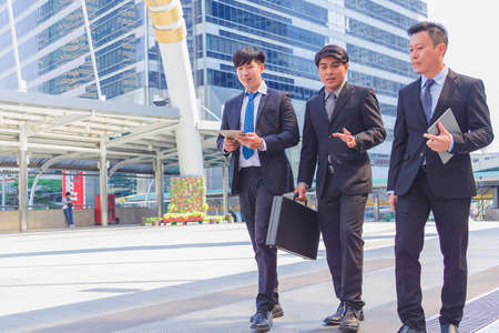 Business team. They are  walking in town. They are talking about business. They are show teamwork  and spirit beside  building background.Photo concept business and relax time.の写真素材