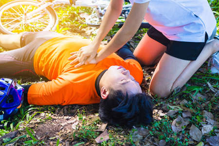 First Aid Emergency is CPR.The man who face heart attack and shock was helped by his friend after the bicycle race. A woman who is his friend give CPR to save his life.Photo concept Emergency and CPR.の写真素材
