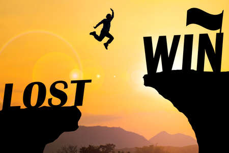 Silhouette sunset background. A man are jumping over to cliff and jump across success word. This...
