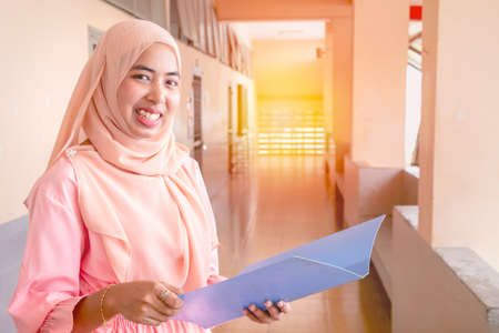 Young student Islamic woman. She is sitting and reading book.She is smile and relax time, woman Portrait, Photo concept portrait and life style.の写真素材