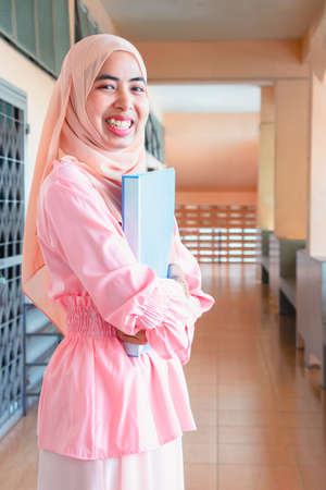 Young student Islamic woman. She is sitting and reading book.She is smile and relax time, woman Portrait, Photo concept portrait and life style.の写真素材