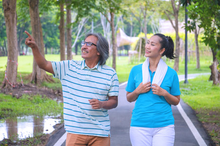 They are happy Asian couple.They  are warm up for exercise in park.They smile and be happy in good time,this photo relates about a husband,wife,love Photo concept Health and relax time.の写真素材