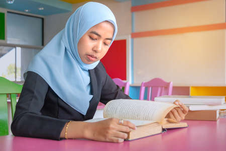 Young student Islamic woman. She is sitting and reading book.She is smile and relax time, woman Portrait, Photo concept portrait and life style.の写真素材