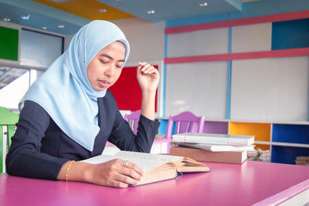 Young student Islamic woman. She is sitting and reading book.She is smile and relax time, woman Portrait, Photo concept portrait and life style.の写真素材