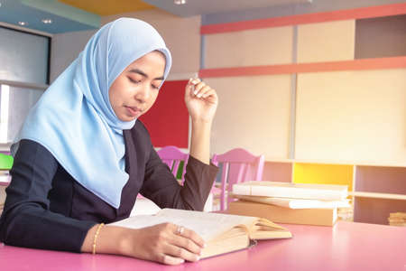 Young student Islamic woman. She is sitting and reading book.She is smile and relax time, woman Portrait, Photo concept portrait and life style.の写真素材