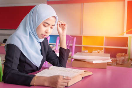 Young student Islamic woman. She is sitting and reading book.She is smile and relax time, woman Portrait, Photo concept portrait and life style.の写真素材