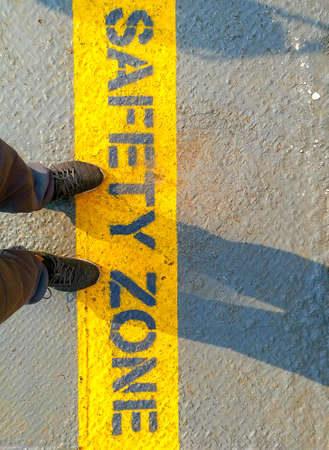 A man standing on â€œarrowâ€ word.He is wearing blue Shout and standing on Metal floor....