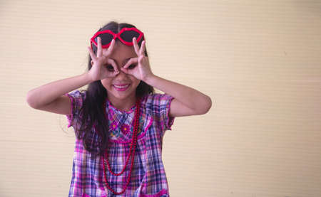 Portrait Asian cute girl. She is sitting with red big glass.She is action in room.Child girl is happy and beautiful.

photo concept freedom  and  Kid portrait.の写真素材
