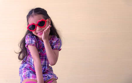Portrait Asian cute girl. She is sitting with red big glass.She is action in room.Child girl is happy and beautiful.

photo concept freedom  and  Kid portrait.の写真素材