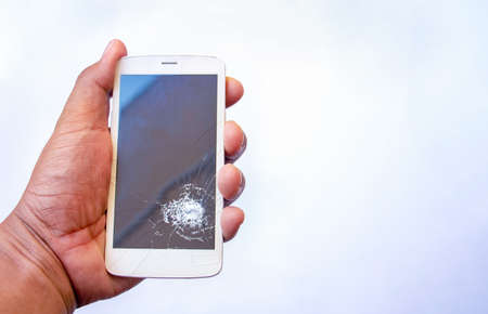 Broken screen smartphone in hand on white background. Close-up.