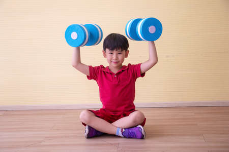 Portrait Asian cute  boy. He is sitting with Dumbbell.He is action in room.Child boy raise dumbbell.lovely,nice,cute,

photo concept freedom  and  Kid portrait.の写真素材