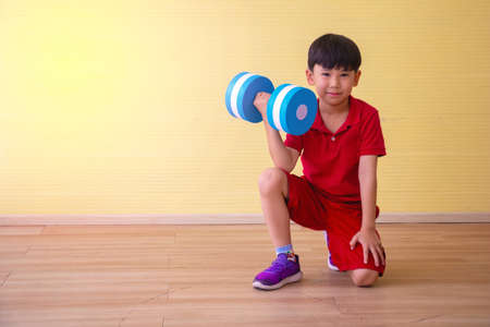 Portrait Asian cute  boy. He is sitting with Dumbbell.He is action in room.Child boy raise dumbbell.lovely,nice,cute,

photo concept freedom  and  Kid portrait.の写真素材