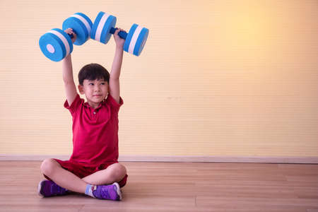 Portrait Asian cute  boy. He is sitting with Dumbbell.He is action in room.Child boy raise dumbbell.lovely,nice,cute,

photo concept freedom  and  Kid portrait.の写真素材