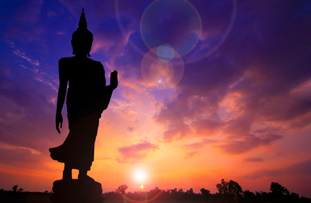 Silhouette photo.Buddha statue standing and show hand.He is standing with sunset. Buddhism,confidence,believe,photo concept Religion and spirit.の写真素材
