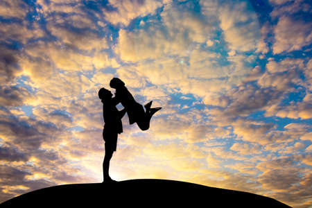Man and woman in love. Man standing and  lift woman They are see the sun set.love, relationship.Photo concept Silhouette and love.の写真素材